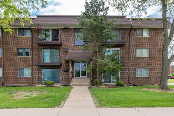 Front view of a three-story brick apartment building with balconies.