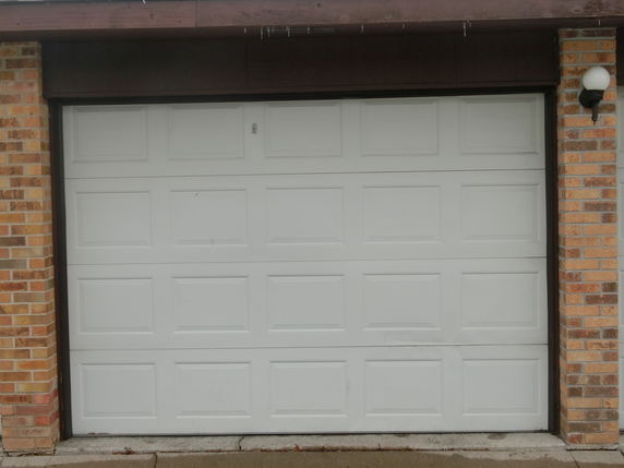 Front view of a garage door with brick walls.