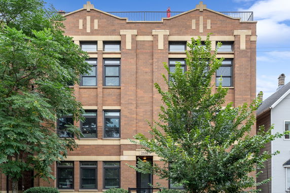 Front view of a multi-story brick building with large windows.
