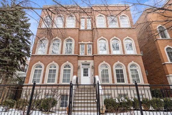 Front view of a three-story brick building with arched windows and a central entrance.