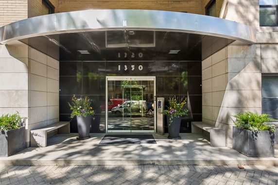 Front entrance of a modern building with glass doors and metal awning.