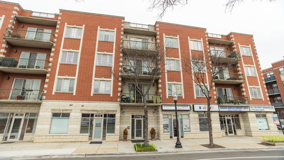 Front view of a multi-story brick building with commercial spaces on the ground floor.