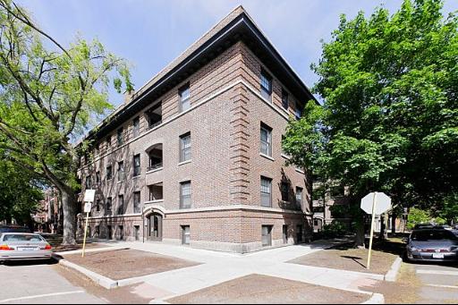 Front view of a multi-story brick building with trees around.