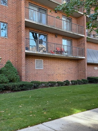 Front view of a multi-story brick apartment building with balconies.