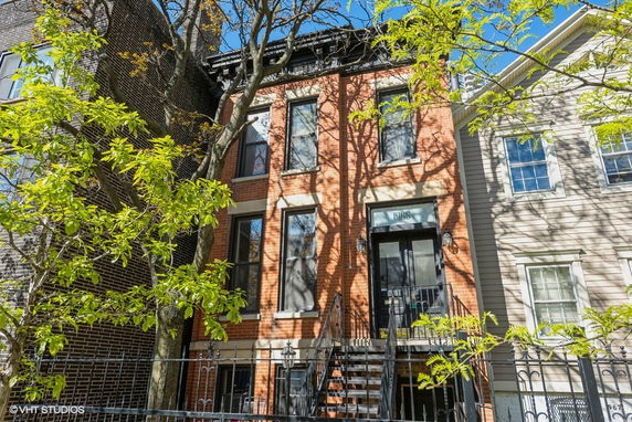 Front view of a multi-story brick building with trees in front.