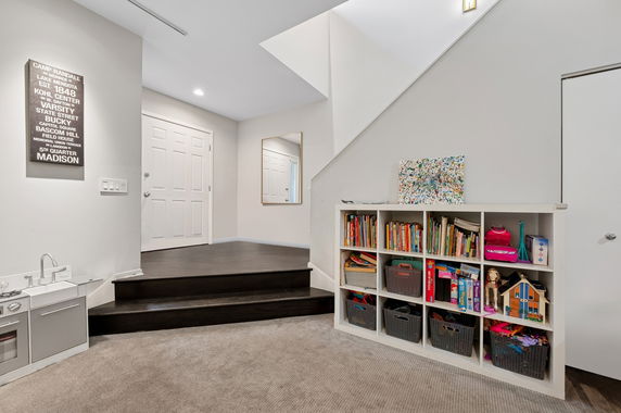 Indoor play area with a bookshelf containing toys and books, and a small play kitchen set.