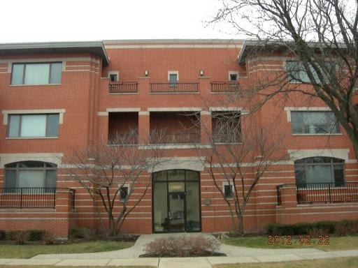 Front view of a three-story brick building with large windows and a central entrance.