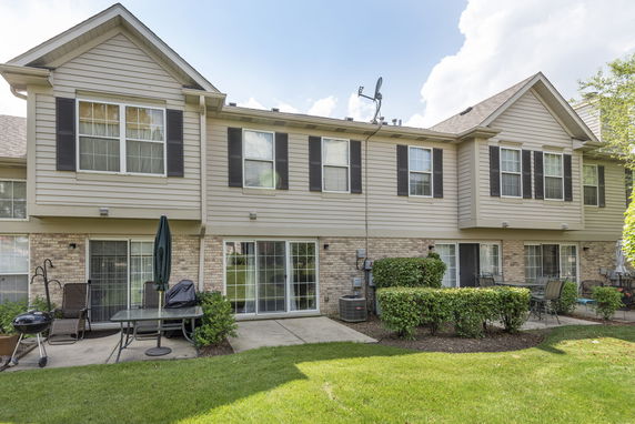 Rear view of a two-story house with sliding glass doors and a small patio.