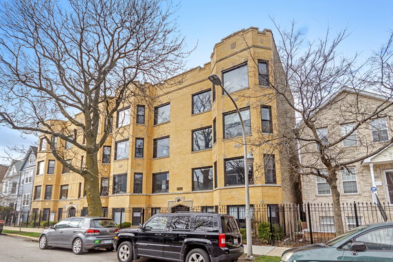 Front view of a multi-story apartment building with yellow brick facade.