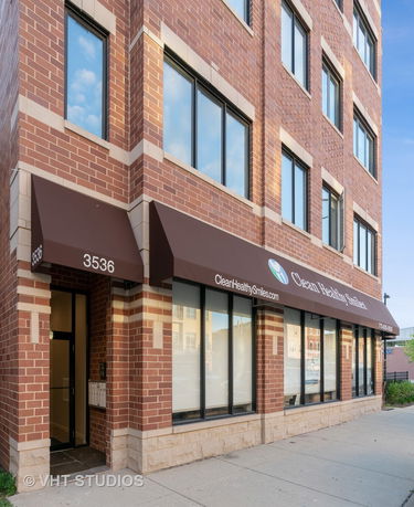 Front view of a brick building with large windows and an awning over the entrance.