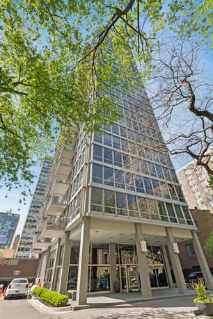 Front view of a modern multi-story building with large glass windows and balconies.