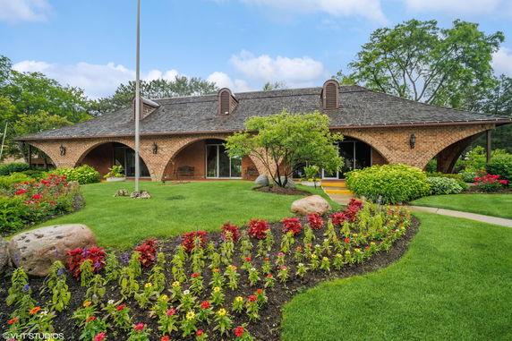 Front view of a house with arched brick design and landscaped garden.