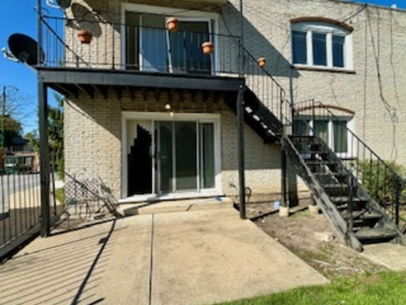 Rear view of a two-story house with external stairs and upper balcony.