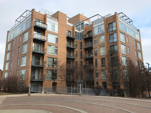 Front view of a multi-story brick apartment building with balconies.