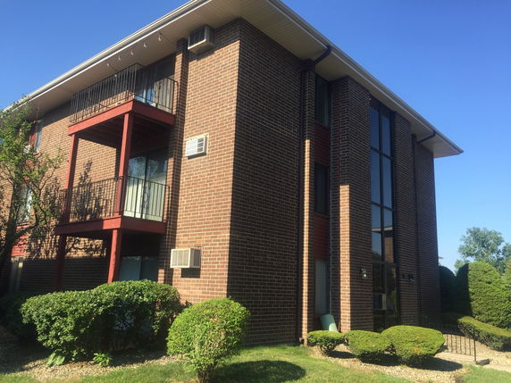 Front view of a multi-story brick building with balconies.