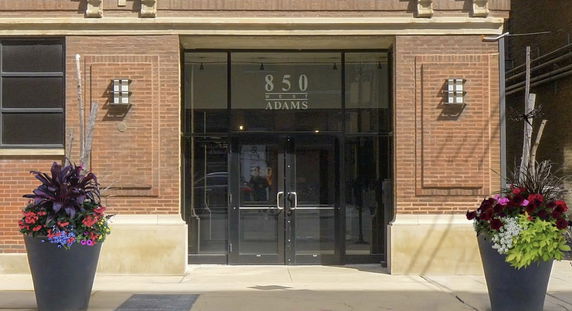 Front view of a brick building entrance with double glass doors.
