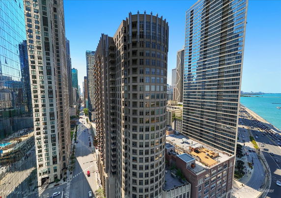 View of tall city buildings with a glimpse of the waterfront in the distance.