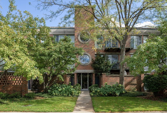 Front view of a multi-story brick building with circular windows and balconies.