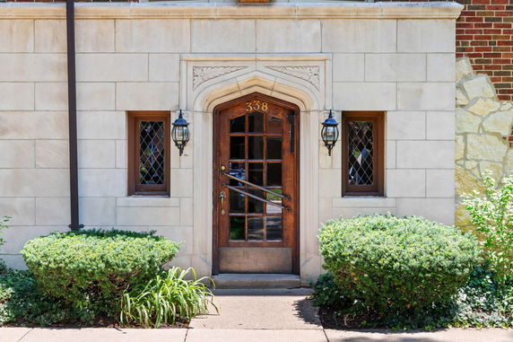 Front view of a building entrance with a wooden door and decorative stonework.