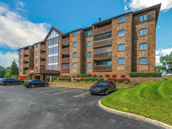 Front view of a multi-story brick apartment building with balconies.
