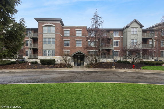 Front view of a three-story brick apartment building with balconies.