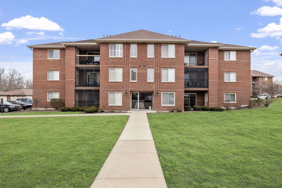Front view of a brick apartment building with three stories and balconies.