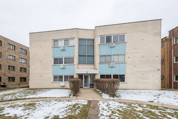 Front view of a two-story apartment building with a central entrance and multiple windows.