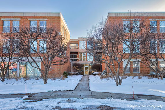 Front view of a brick building with trees in front, set in a snowy landscape.