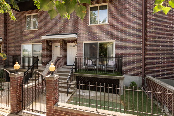 Front view of a two-story brick townhouse with steps leading to a patio area.