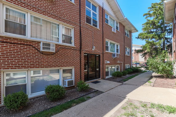 Front view of a three-story brick apartment building with multiple windows and air conditioning units.