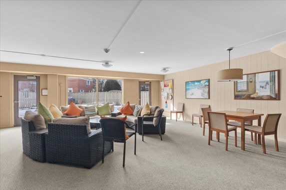 Interior view of a clubhouse with seating area and table with chairs.
