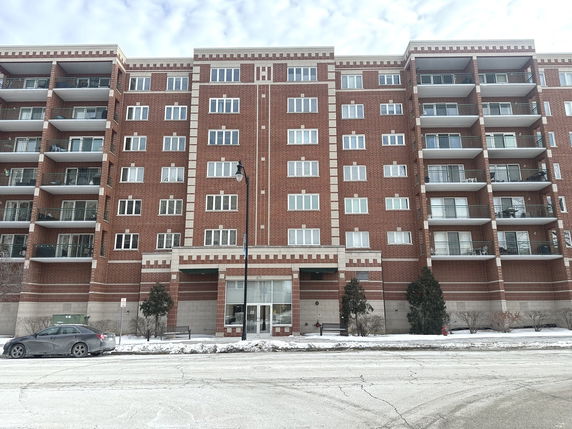 Front view of a multi-story brick apartment building with balconies.