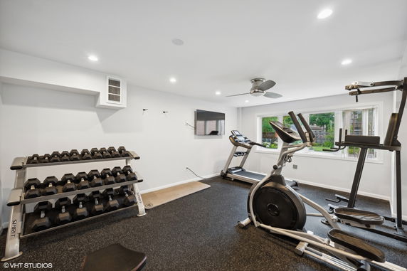 Indoor gym area with exercise equipment including a treadmill, elliptical machine, and dumbbell rack.