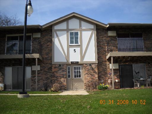 Front view of a two-story building with brick facade and decorative wooden beams.