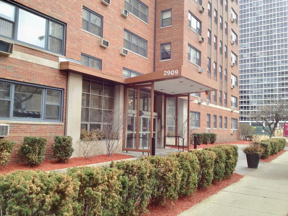 Front view of a multi-story brick building with a glass entrance.