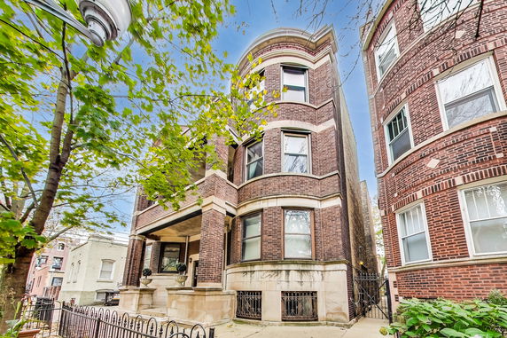 Front view of a multi-story brick building with bay windows.