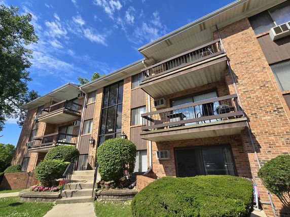 Front view of a multi-story residential building with balconies and brick exterior.