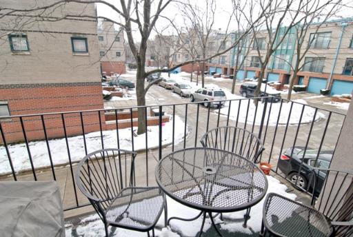 View from a balcony overlooking a parking area and townhouses.