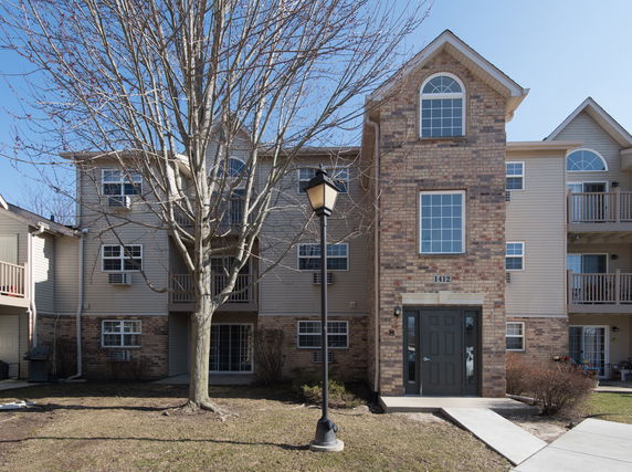 Front view of a multi-story residential building with brick and siding exterior.