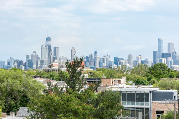 Panoramic view of a city skyline with skyscrapers and greenery in the foreground.