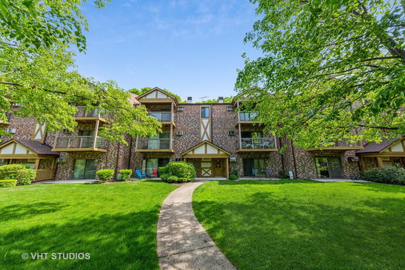 Front view of a three-story brick apartment building with balconies.