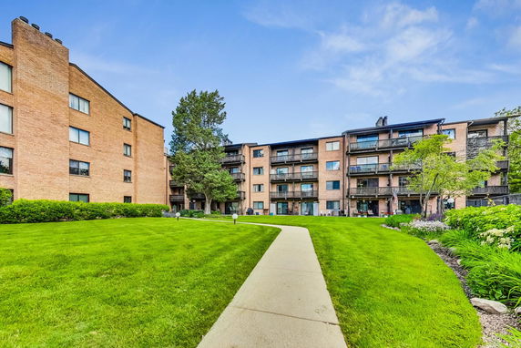 Front view of a multi-story brick apartment building with balconies.