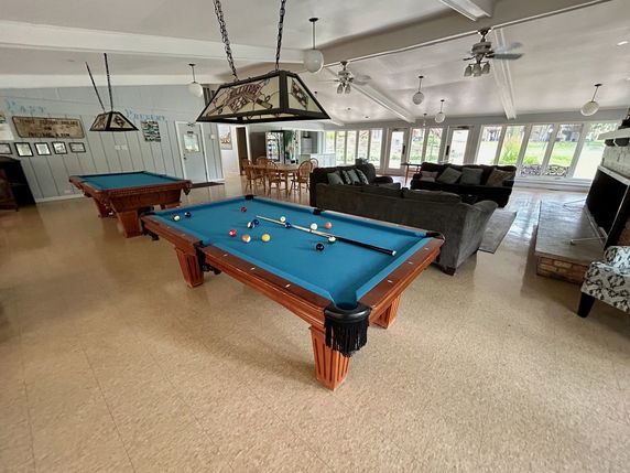 Interior view of a recreation room with pool tables and seating area.