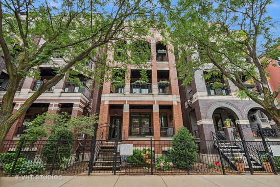 Front view of a multi-story brick apartment building with balconies.