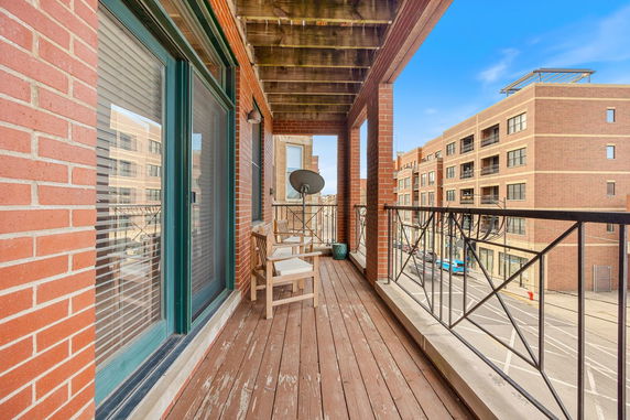 View of a balcony attached to a brick building overlooking a street and other buildings.