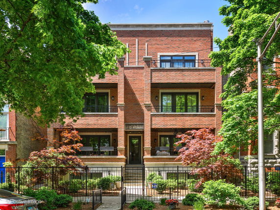 Front view of a multi-story brick building with balconies and a gated entrance.