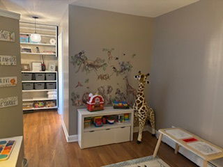 Room decorated as an indoor play area with toys and animal decals on the wall.