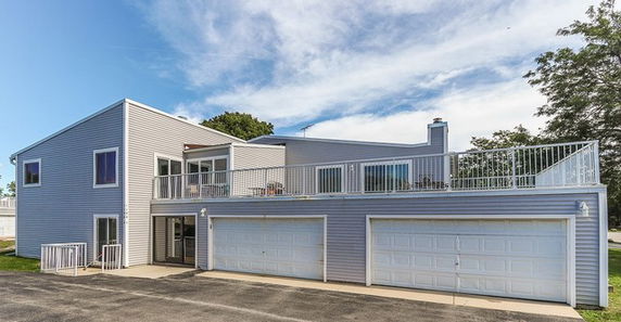Front view of a two-story house with multiple garages and a rooftop patio.