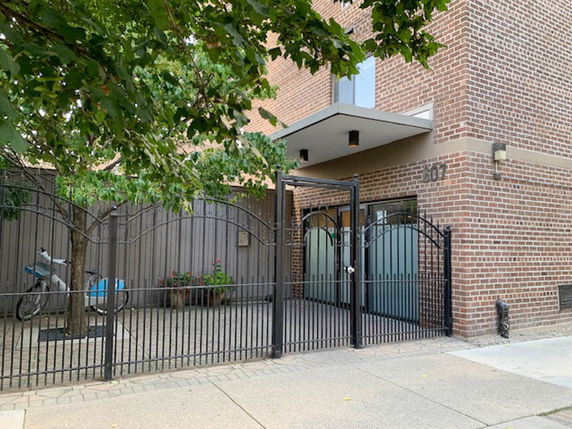 Front view of a brick building with a metal gate entrance.