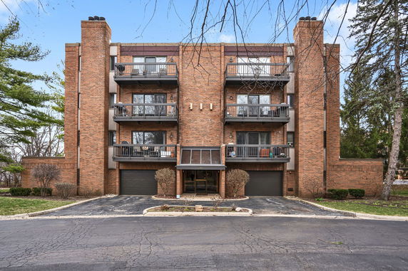 Front view of a multi-story brick building with balconies and a central entrance.